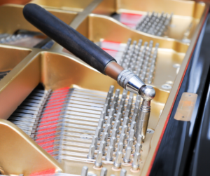 Photo of the inside of a piano with a tuning tool